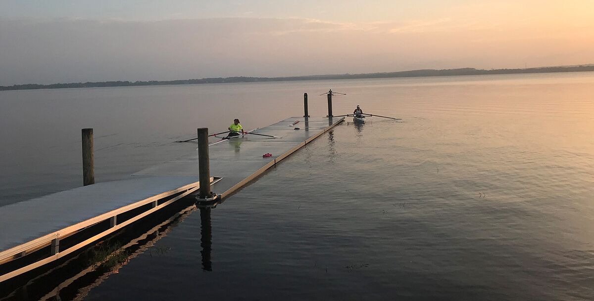 Three rowing athletes paddle to low-profile floating docks for rowing for easy of exit.