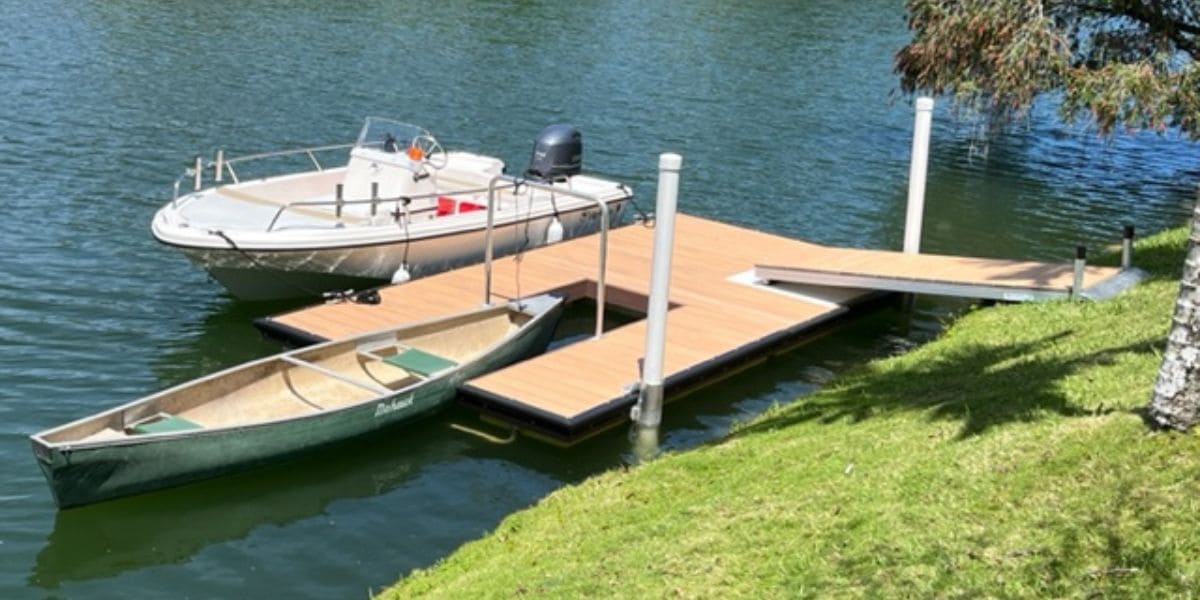 A small dock with a canoe and a motorboat on a calm lake, illustrating key differences in watercraft use and space in the canoe vs kayak debate.