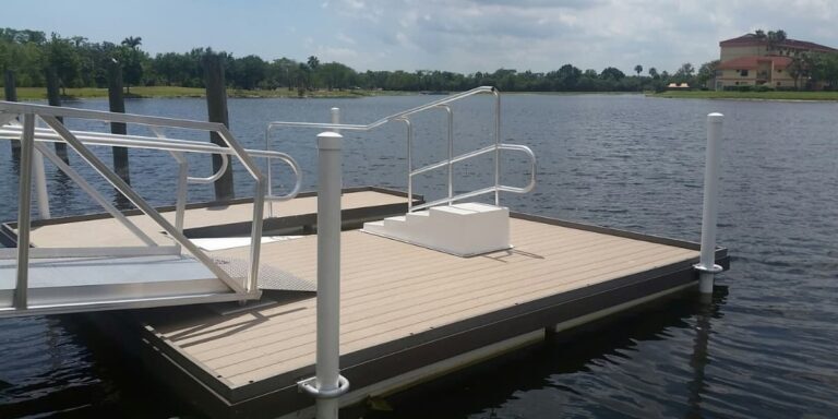 Floating dock stability shown by a wide modular dock with ramp and handrails on calm water near shoreline buildings