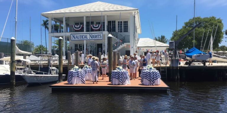 Guests enjoying a waterfront dock party with nautical-themed tables and striped decor at a marina under sunny skies.