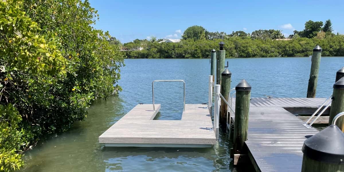 Floating dock on calm water surrounded by greenery, ideal for paddleboarding and kayaking, featured in water sports gift guide.