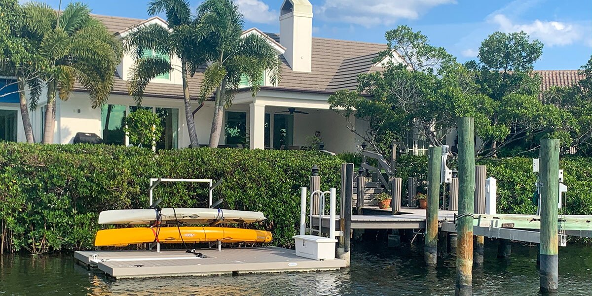 A floating dock with kayaks on a rack next to a dock box filled with equipment.