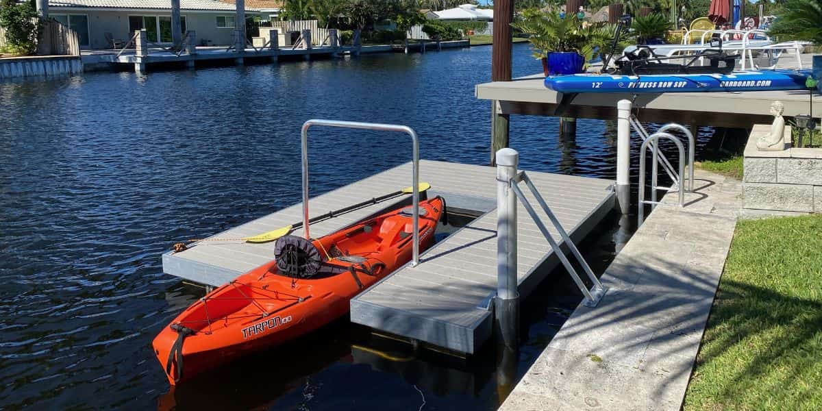 Red sit-on-top kayak on a floating dock with calm water in the background, showcasing the best kayak for beginners for stability and ease of use.