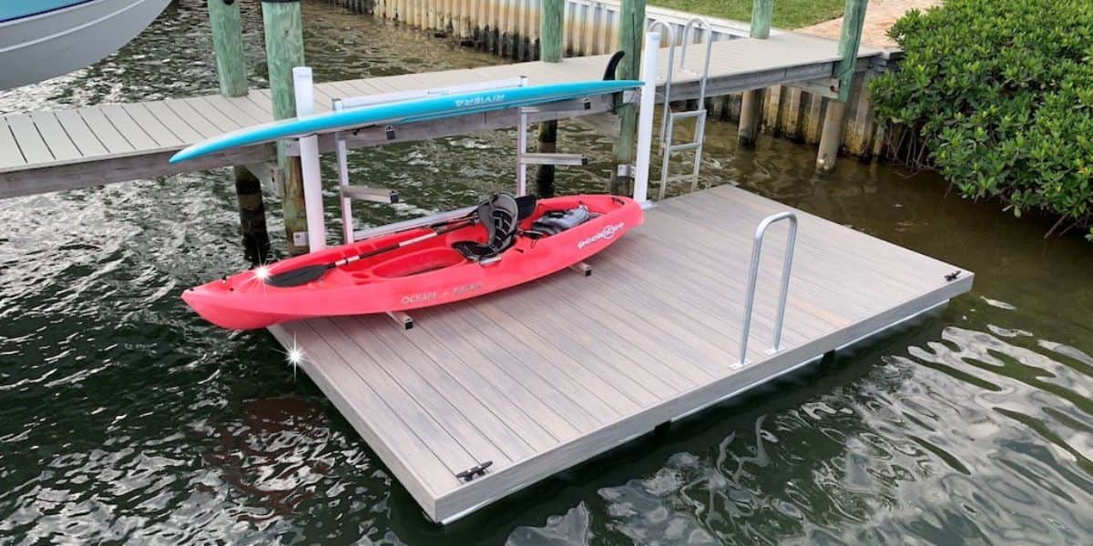 Kayak storage setup on a floating dock featuring a red kayak and blue paddleboard securely placed on a metal rack, demonstrating an organized and safe storage solution