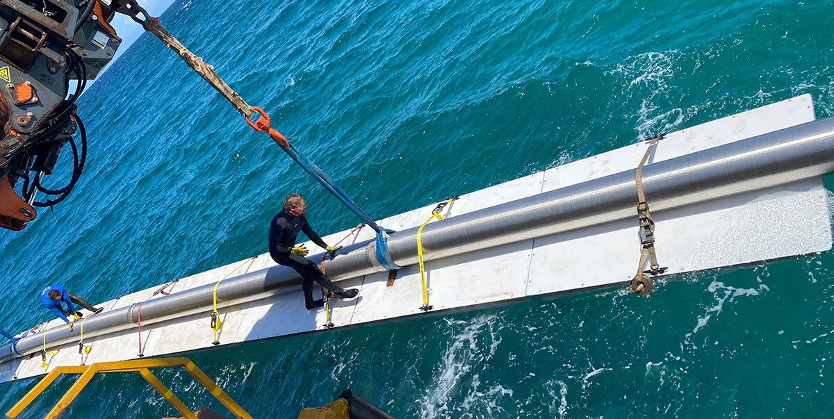 Labor workers moving pipes along industrial docks made from AccuDock's modular floating docking system.