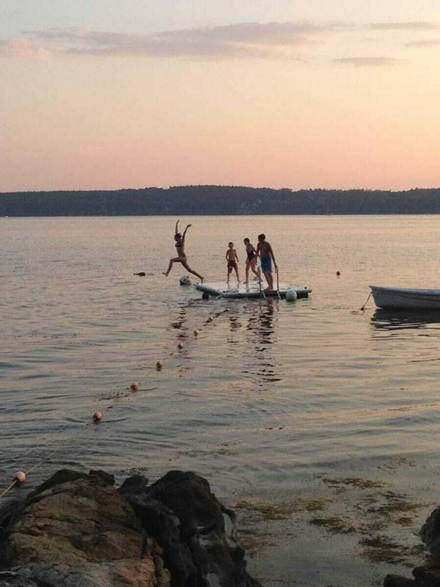 people jumping off a swimming platform in the middle of a lake