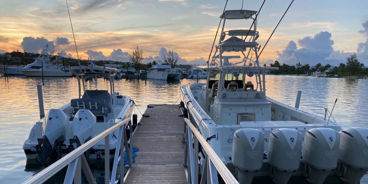 An Accudock floating boat dock for sale with two vessels on either side facing a sunset.